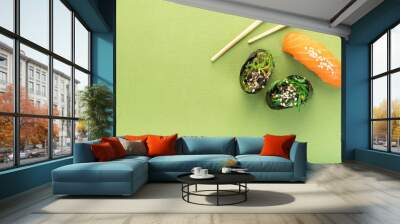 Two Chuka seaweed Sushi and salmon nigiri with chopsticks on a green background, top view Wall mural