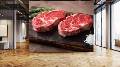 Two fresh raw rib-eye steak on wooden Board on wooden background with salt, pepper and rosmary in a rustic style Wall mural