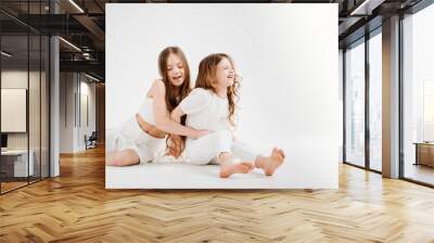 two little girls with long hair in white clothes. love between sisters.  Wall mural