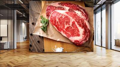 Two raw rib eye steak on a wooden Board on a table prepared for the grill. Top view rustic style Wall mural