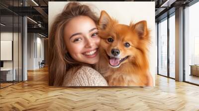 Young smiling happy cheerful owner woman with her best friend dog isolated on light colored background  Wall mural