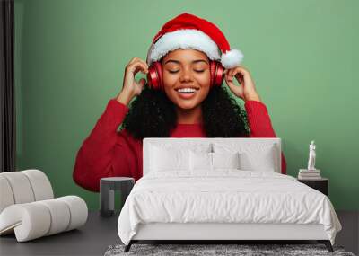 young woman in santa hat with headphones enjoying music on christmas Wall mural