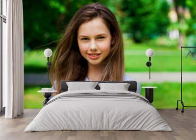 Portrait of a young beautiful brunette  girl in summer park Wall mural