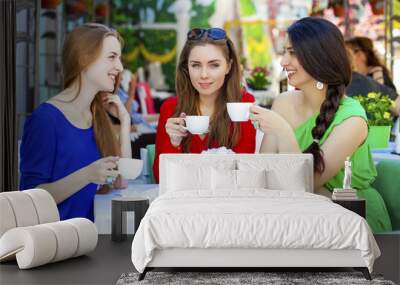 Three happy girlfriends woman sitting at a table in the summer c Wall mural