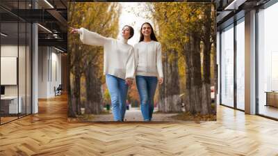 Two girlfriends in a white woolen sweater and blue jeans Wall mural