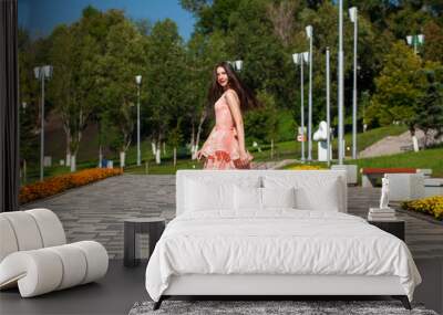 Young beautiful woman in pink dress walking on the summer street Wall mural