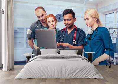 A group of young medical students with mixed-race surgeons examining these operations in a laptop Wall mural