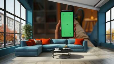 Man lying on couch using smartphone with chroma key green screen at night, scrolling through social media or online shop - internet, communications concept close up  Wall mural