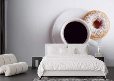 Top view of a white cup filled with coffee on a saucer and a donut lying next to it in powdered sugar on a white background. Copy space. Wall mural