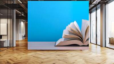 The book is open, lying on the table, sheets fanned out on a blue background. Wall mural