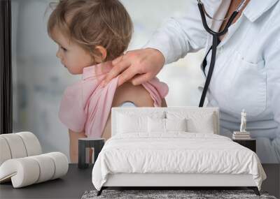 Pediatrician doctor examining a little girl by stethoscope Wall mural