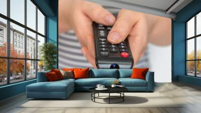 Remote control in female hands pointing to TV Wall mural