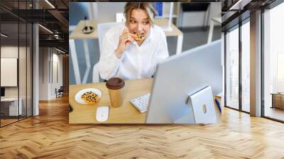 Business woman in a hurry is forced to snack on cookies while working at the computer Wall mural