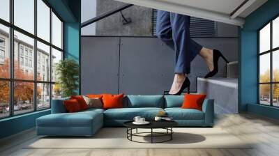 Close-up of a business woman's legs in pants and high-heeled shoes walking down the stairs Wall mural