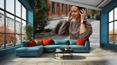 Portrait of adult athletic woman wearing headphones and listening to music outdoors Wall mural