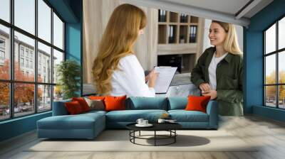 Two female doctor and patient talking in a modern private clinic Wall mural