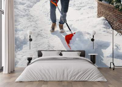 A young man clears the snow in front of the house on a sunny and frosty day. Cleaning the street from snow. Wall mural