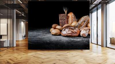 Assortment of fresh baked bread on dark background. White and rye bread, buns with copy place Wall mural