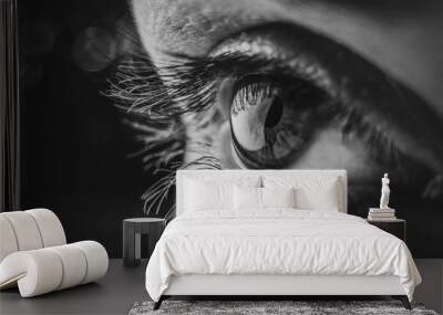 Black and white macro photo Eye of a European woman with eyelashes, pupil in a low key. Shine in the pupil of the eye close-up with soft focus. Wall mural