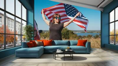 Happy woman holding USA flag and enjoying the sunset in nature. Free lifestyle Wall mural