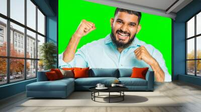 Happy joyful Indian man celebrating success victory, winning birthday, lottery jackpot goal achievement play game good positive news, triumph. Young Arabian guy isolated on green chroma key background Wall mural