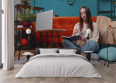 Young woman doing, planning home budget and counting money, girl checking dollar cash to pay utility bills. Young girl reviewing invoices on laptop computer, doing family business plan and tax return Wall mural