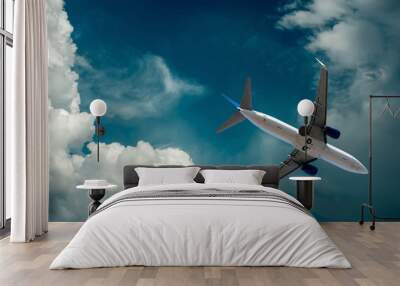 Airplane at flying under sky with clouds Wall mural