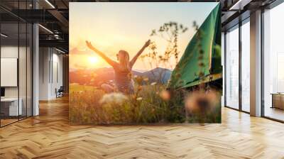 Happy woman with open arms stay near tent around mountains under sun Wall mural