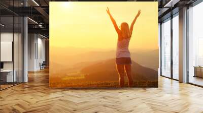 Happy woman with open arms stay on the peak of the mountain  Wall mural