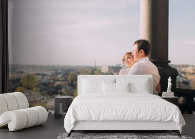 Beautiful wedding couple newlyweds hugging on balcony with view of the old city Wall mural