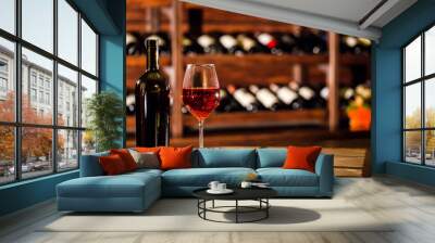 Composition of wine bottle and wine glass. Shelves with wine bottles on the background. Wall mural