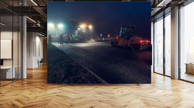 Laying asphalt paver at night with headlights. Road construction. Wall mural