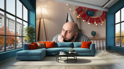 Caucasian single man sit at home on party alone no guests celebrating lonely birthday. Sad unhappy bearded male in loneliness Wall mural