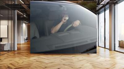 Handsome male driver driving car and drinking takeaway coffee. Lifestyle and people concept Wall mural