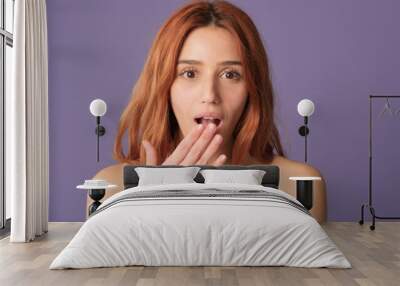 Close-up of red-haired woman looking at mirror in studio on purple background, POV shot. Beautiful girl poses in studio with blank space on violet wall for your promotion Wall mural