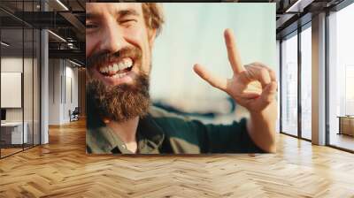 Closeup portrait of a smiling man with a beard chatting on the embankment, on a yacht background. Frontal close-up of happy young male hipster using mobile phone Wall mural