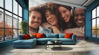 Happy smiling friends make a video call from a mobile phone. Four students wave their hands in greeting Wall mural