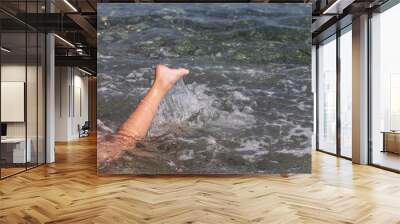 Closeup view horizontal photography of kids legs splashing in blue sea water outside swimming and enjoing summer beach vacations. Wall mural