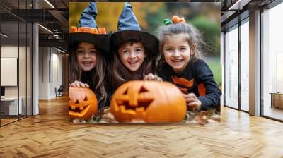 Three children in witch hats carving pumpkins outdoors in autumn Wall mural