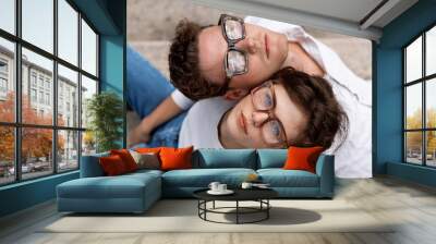 two attractive students man and woman wearing stylish glasses sitting floor Wall mural