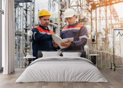 Two specialist electrical substation engineers inspect modern high-voltage equipment in the evening. Energy. Industry Wall mural