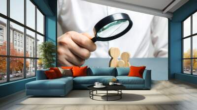 A man looks through a magnifying glass at a family figure. The study of family composition and demographic situation. Statistical data. The program of support for young families, financial assistance. Wall mural