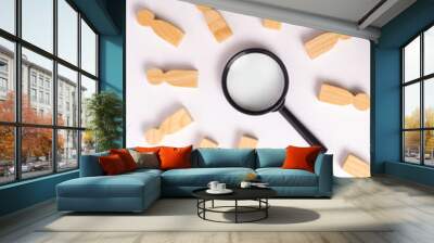 Wooden figures of people lie around a magnifying glass on a white background. Hiring for work, tracing people. The concept of the search for people and workers, human resources. Wall mural