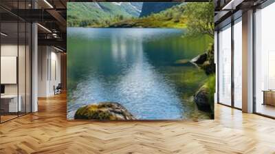 A beautiful lake surrounded by mountains and rocks. The water is calm and clear, reflecting the sky and the mountains. The scene is peaceful and serene, inviting one to sit and enjoy the view Wall mural