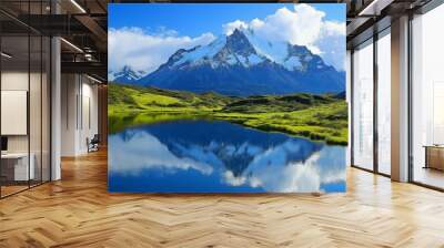 A beautiful mountain landscape with a lake in the foreground. The lake is calm and reflects the mountains in the distance. The sky is clear and blue, and the mountains are covered in snow Wall mural