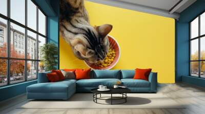 A cat is eating from a bowl of food Wall mural