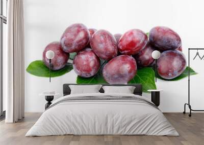 A group of ripe red-purple plums with leaves on a white background. Wall mural