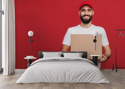 A man with a red hat and beard is holding a cardboard box. He is smiling and he is happy Wall mural