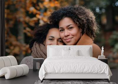 A mother and teenage daughter laughing and taking a selfie together in an park area. Wall mural