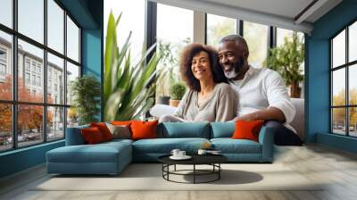 A relaxing and laughing black senior couple, sharing affection and friendship in a cozy home setting. Wall mural